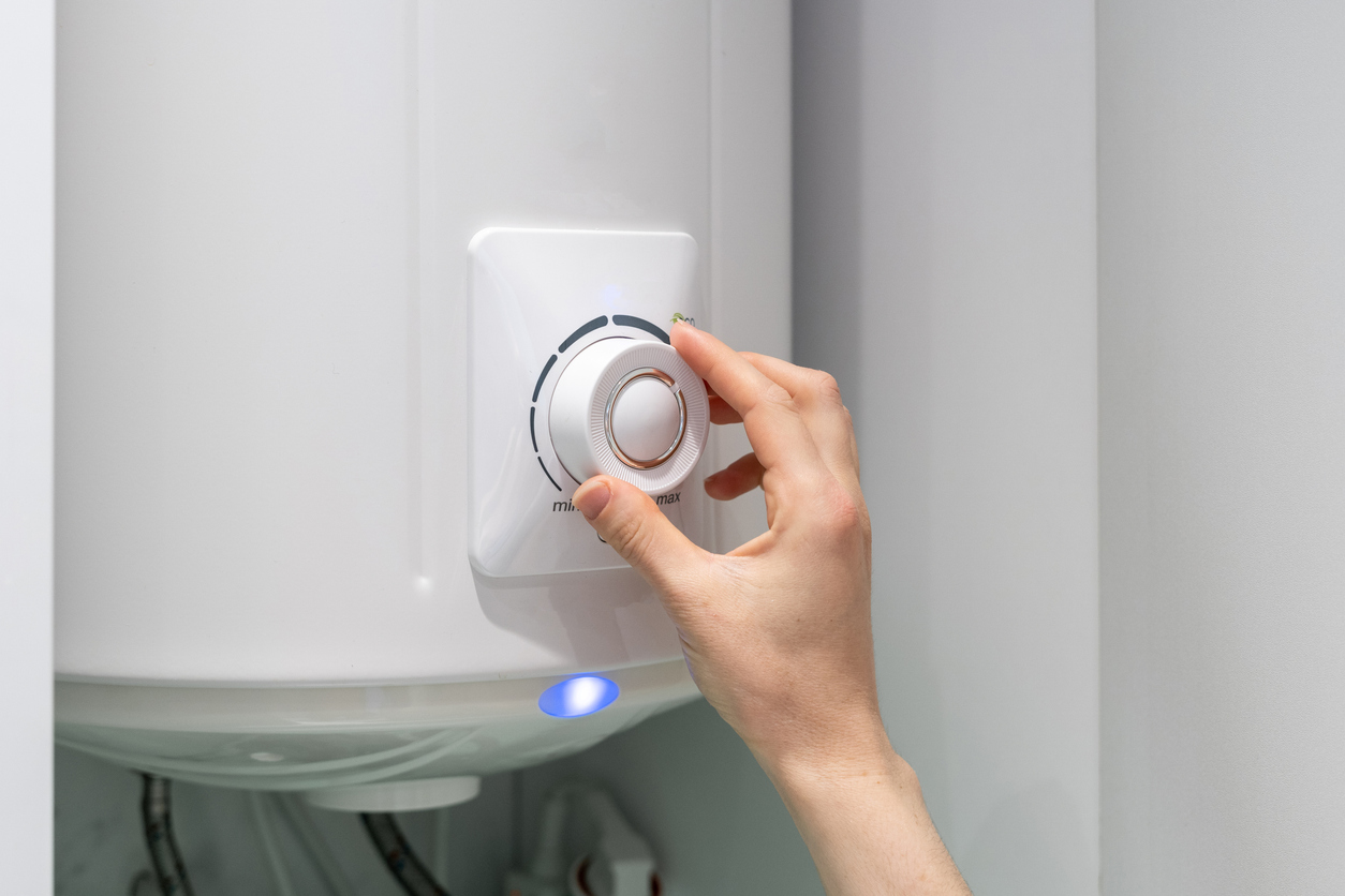 Homeowner's hand on the temperature knob on a residential boiler